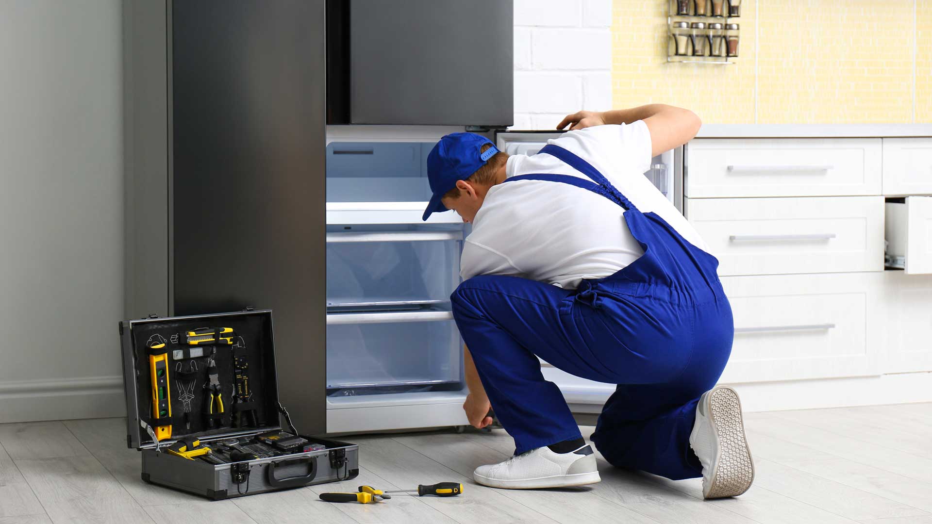 Man repairing freezer drawer on refrigerator
